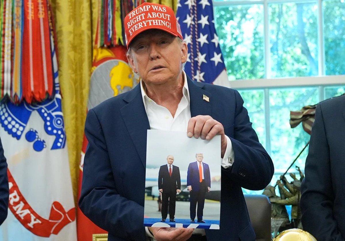 Trump proudly showing a photo of himself with war criminal Vladimir Putin
